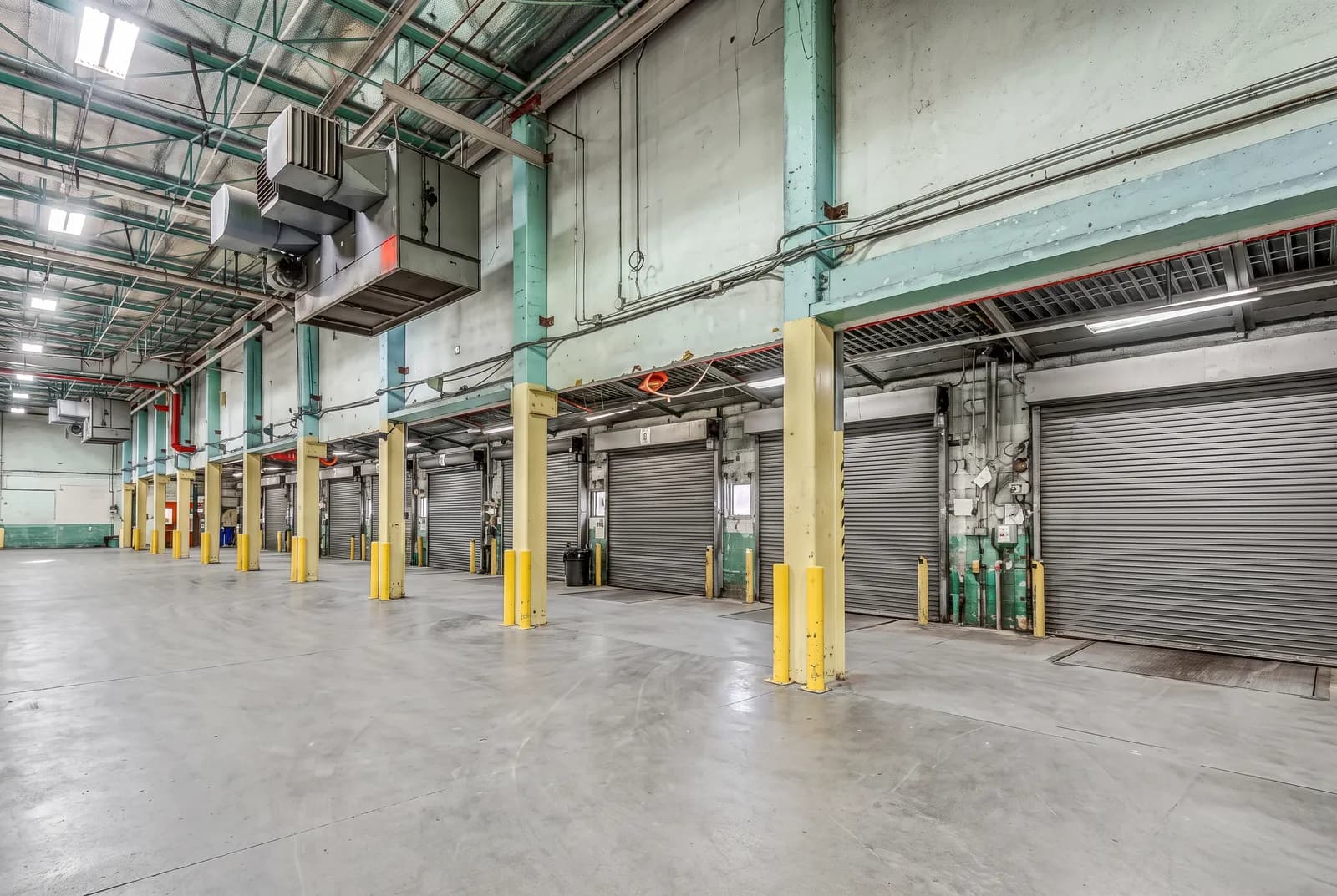 Inside the Vancouver dock wall: a row of roll-up dock doors, guarded columns and clear floor