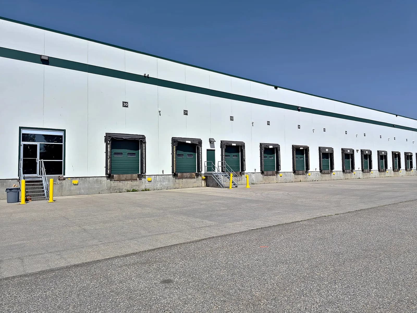 The Rolls Right Calgary warehouse seen from the truck court, the office entrance at left and the numbered dock doors running down the wall